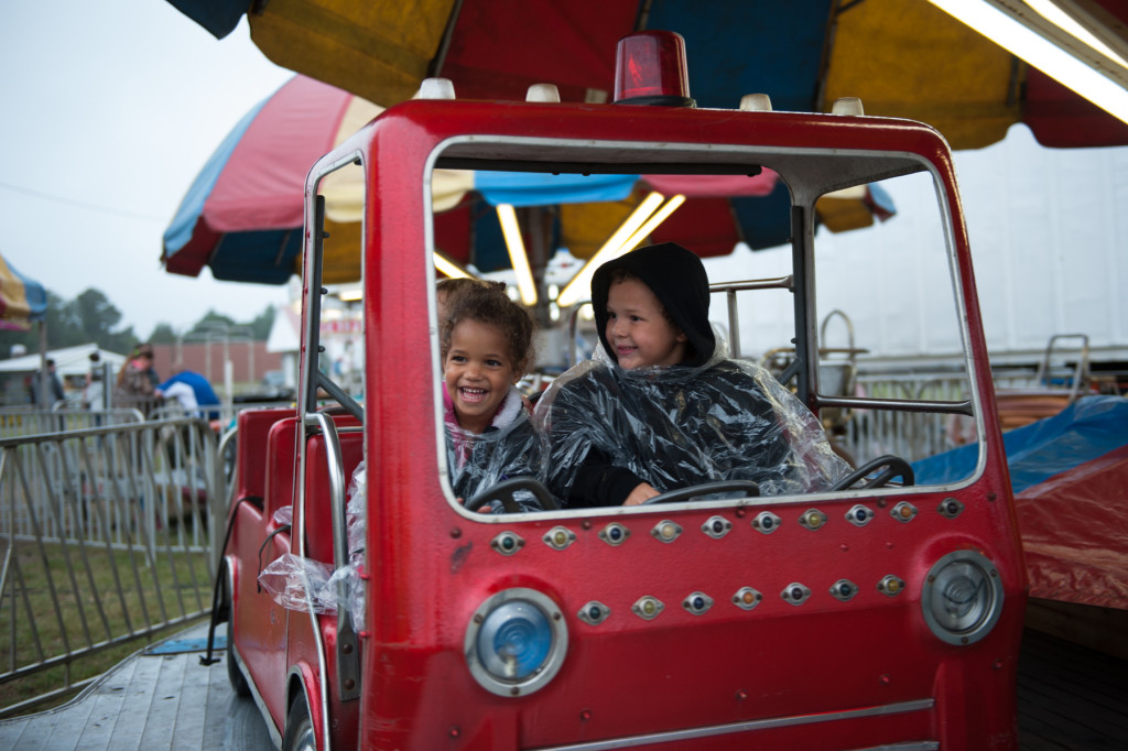 Three-year-old Jada Phillips (left) and 5-year-old Zeke Phillips (right) ride  in a fire-engine on a carousel  at the Moore County Fair on Thursday, October 1, 2015 in Carthage, North Carolina.